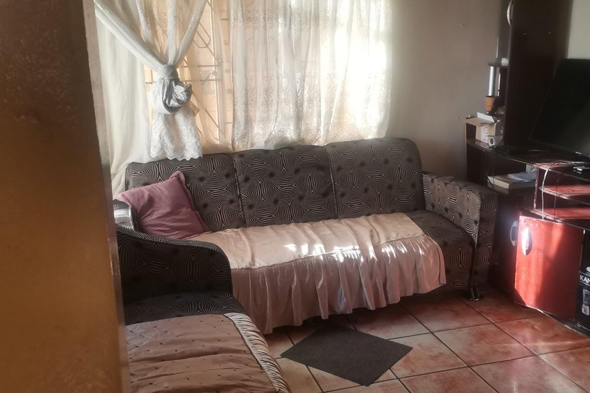 A living room area featuring tiled flooring and window security bars, providing a functional space for relaxation.