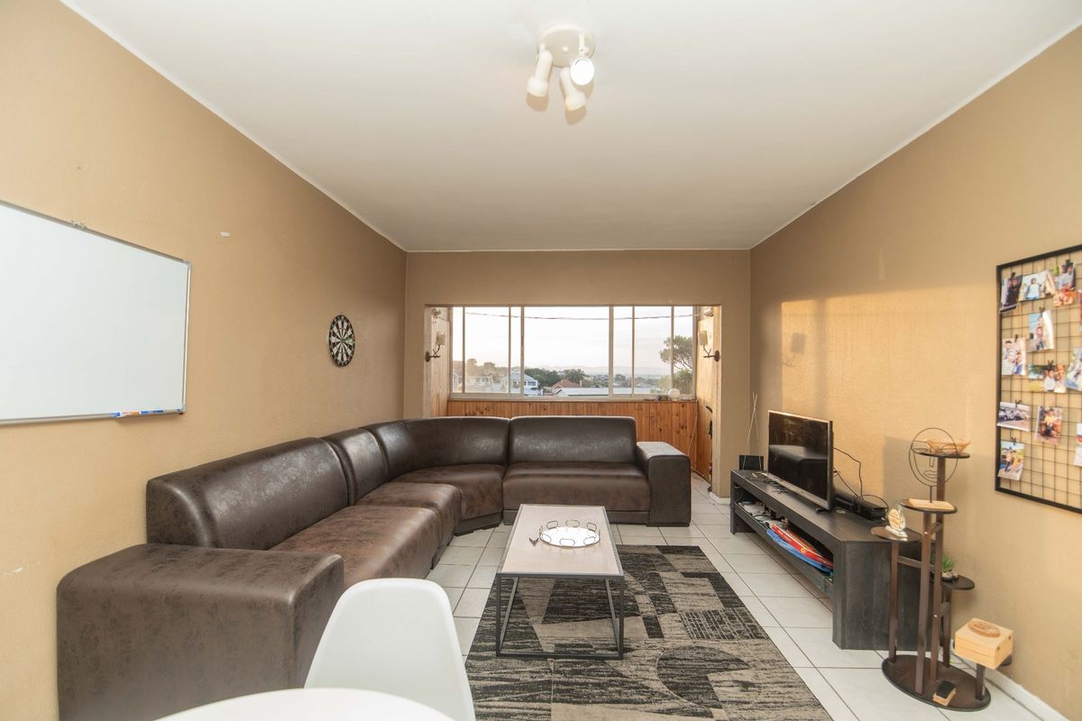 A functional living room featuring tiled flooring and a large window that provides natural light and views.
