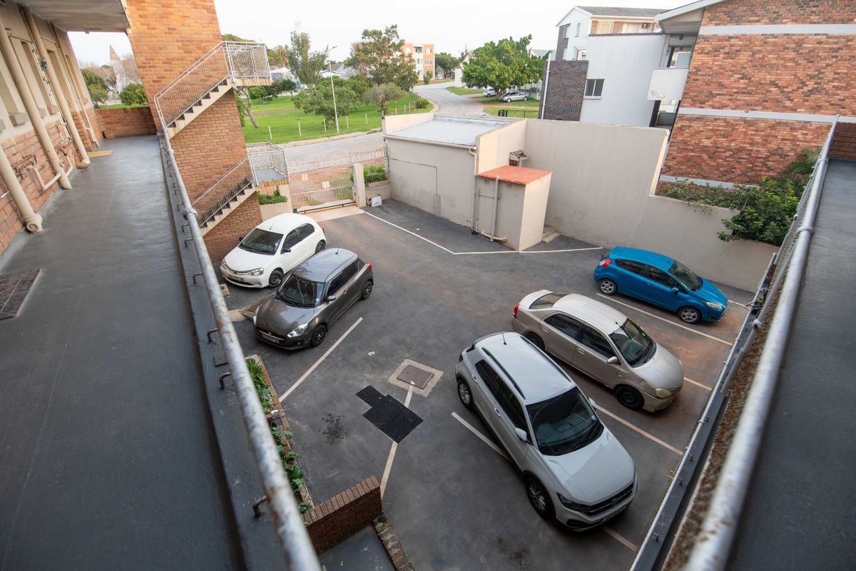 An elevated view of the apartment complex rear parking area featuring brick building facades and a metal staircase.