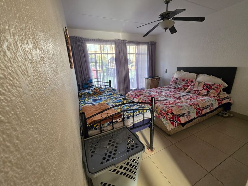 A bedroom featuring tiled flooring, a ceiling fan, and a sliding glass door providing natural light.