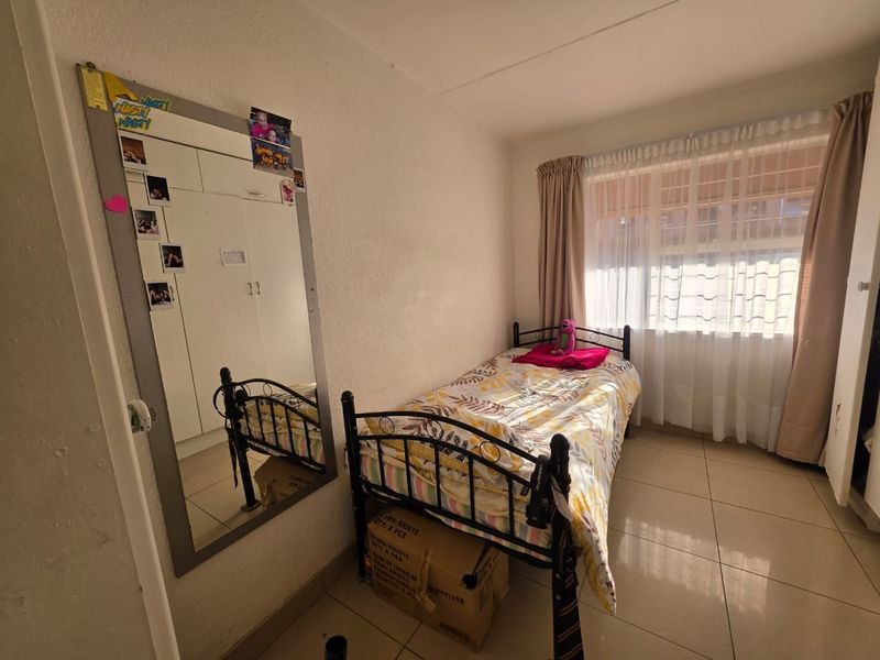 A compact bedroom featuring tiled flooring and built-in cupboards, providing functional storage space.