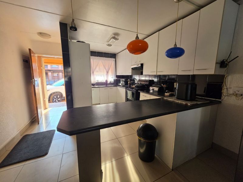 Functional kitchen featuring white cabinetry, black countertops, a breakfast bar, and tiled flooring, with direct access to the exterior.
