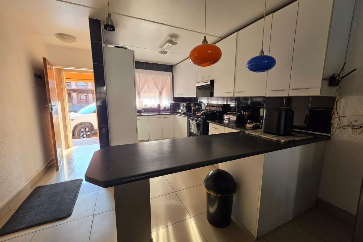 Functional kitchen featuring white cabinetry, black countertops, a breakfast bar, and tiled flooring, with direct access to the exterior.