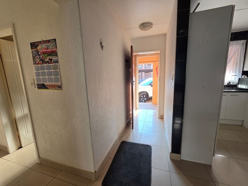 An entry hallway with tiled flooring leading to the main entrance, providing access to adjacent living and kitchen areas.
