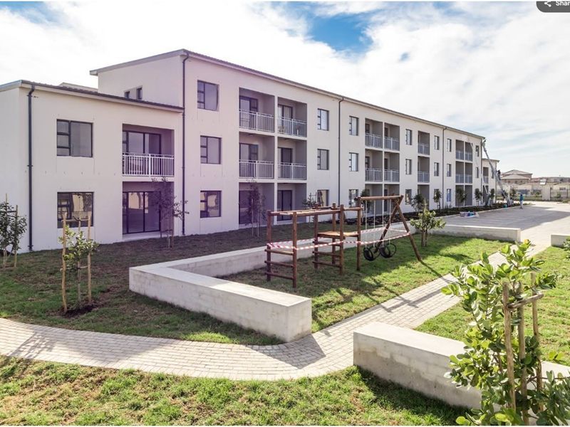 Exterior view of a modern apartment complex featuring private balconies, paved pathways, and a communal garden area with concrete landscaping elements.