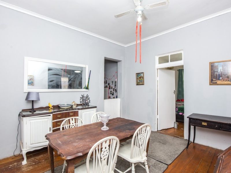 Dining room featuring original hardwood flooring, coved cornicing, and a ceiling fan, requiring minor cosmetic updates to the wall finishes.