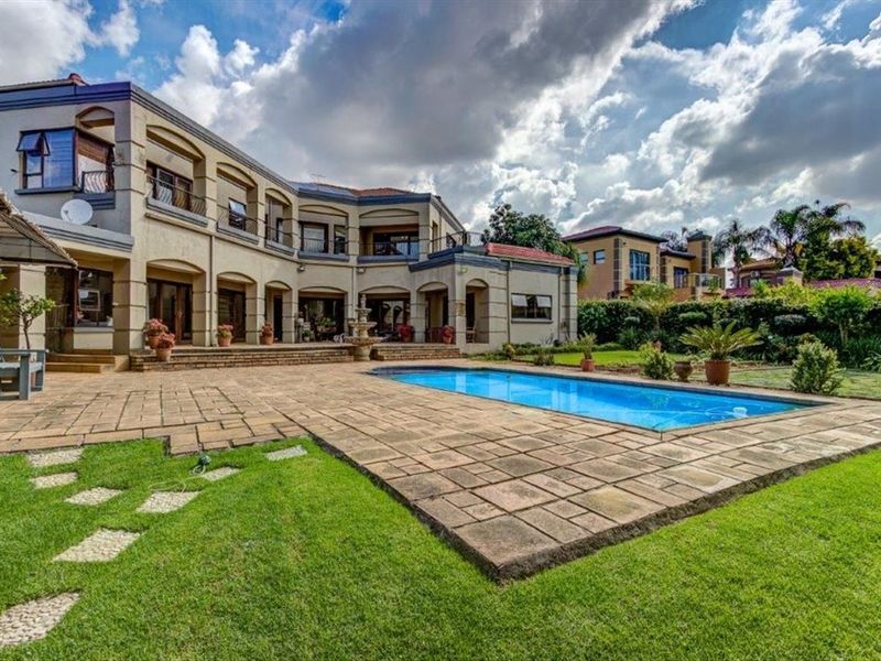 Spacious rear exterior featuring a large paved patio, swimming pool, landscaped garden, and a multi-level residence with balconies.