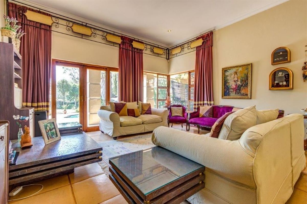 Spacious living room featuring terracotta floor tiles, recessed lighting, and large sliding glass doors providing direct access to the outdoor pool area.