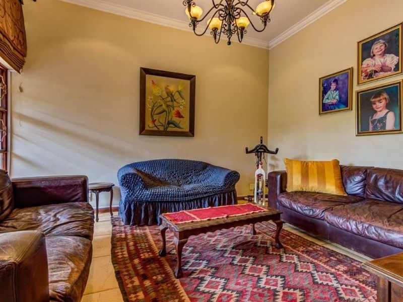 A comfortable living room featuring crown molding, tiled flooring, and a decorative wrought iron chandelier, providing a classic and inviting atmosphere.