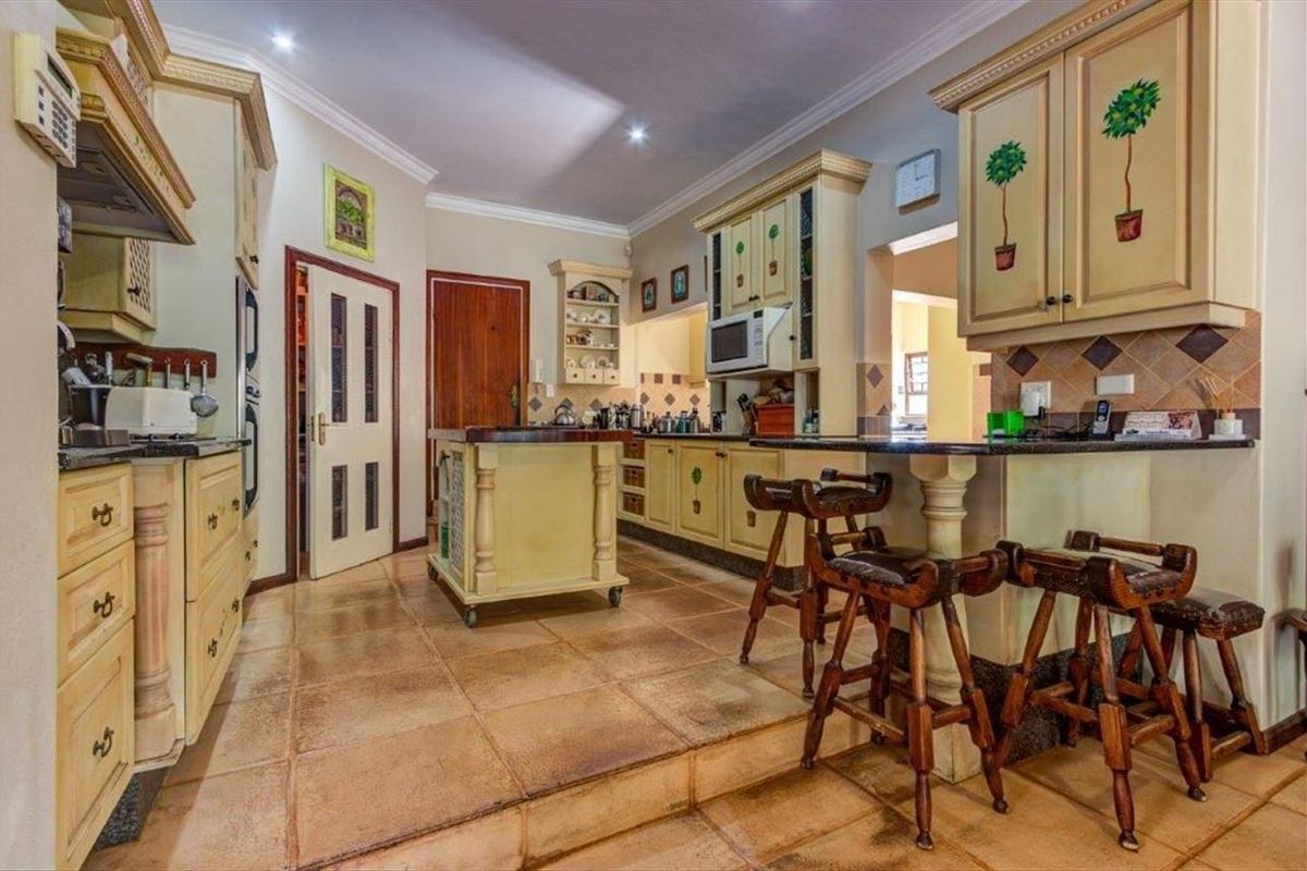 Spacious kitchen featuring custom painted cabinetry, granite countertops, a central island, and tiled flooring with a raised breakfast bar area.