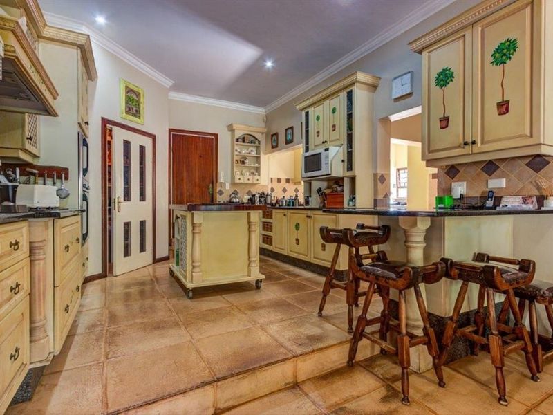 Spacious kitchen featuring custom painted cabinetry, granite countertops, a central island, and tiled flooring with a raised breakfast bar area.