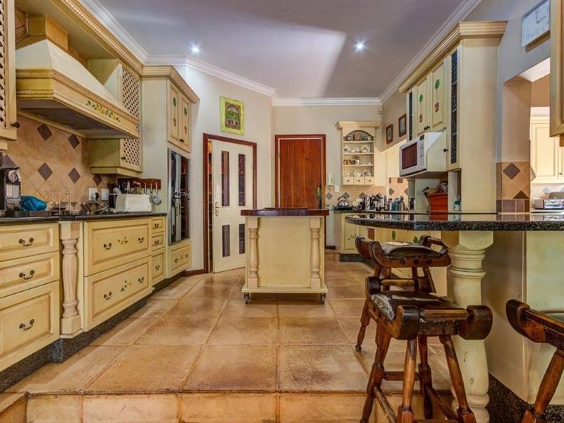 Spacious kitchen featuring traditional cabinetry, granite countertops, a central island, and tiled flooring, offering a functional layout with ample storage space.