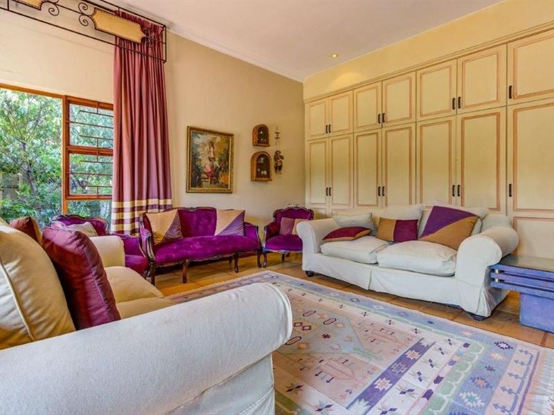 A spacious living room featuring extensive built-in cabinetry, tiled flooring, and large windows that provide natural light and garden views.