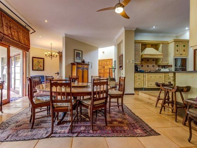 Spacious open-plan living and dining area featuring tiled floors, a ceiling fan, and a traditional kitchen with built-in cabinetry and a breakfast bar.