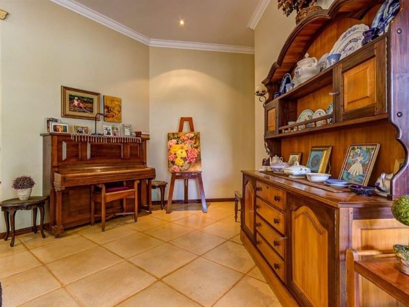 A living area featuring neutral wall tones, tiled flooring, and decorative crown molding, providing a classic foundation for various interior design styles.