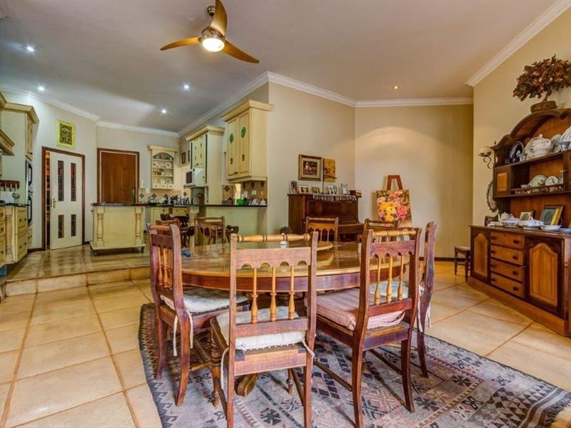 Spacious open-plan living and dining area featuring tiled flooring, recessed lighting, and a functional kitchen with built-in cabinetry.