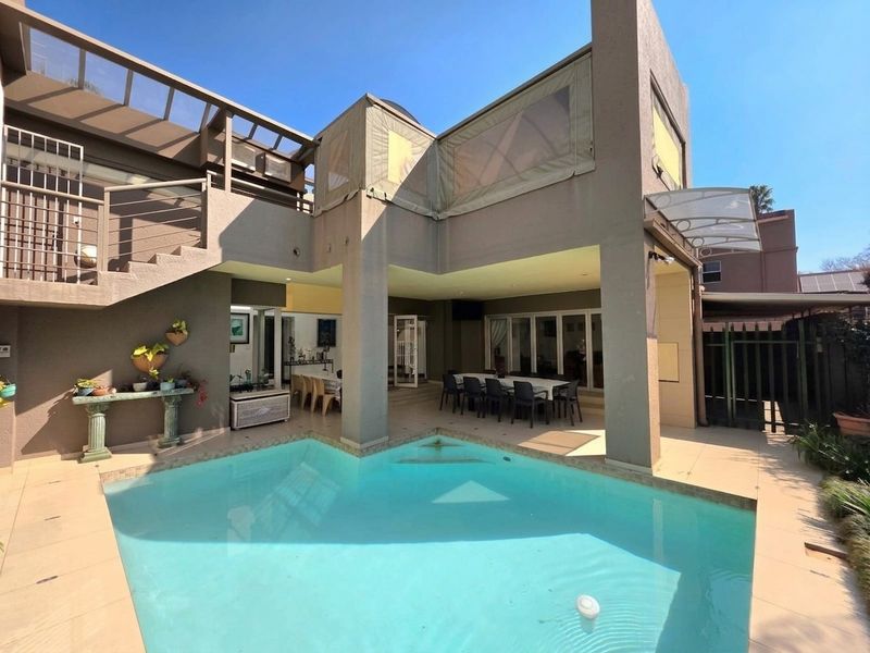 Spacious outdoor entertainment area featuring a swimming pool, covered patio, and an external staircase leading to an upper balcony.