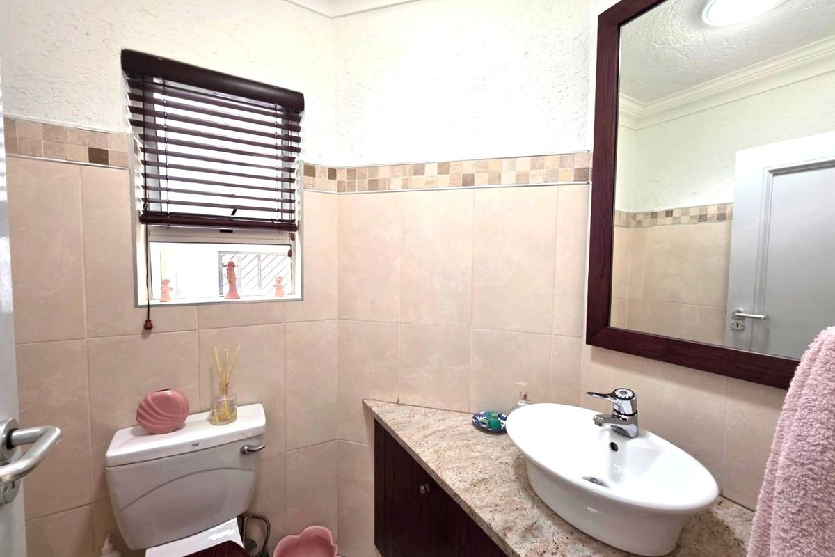 A well-maintained bathroom featuring a granite-topped vanity with a vessel sink, tiled walls, and a framed mirror.