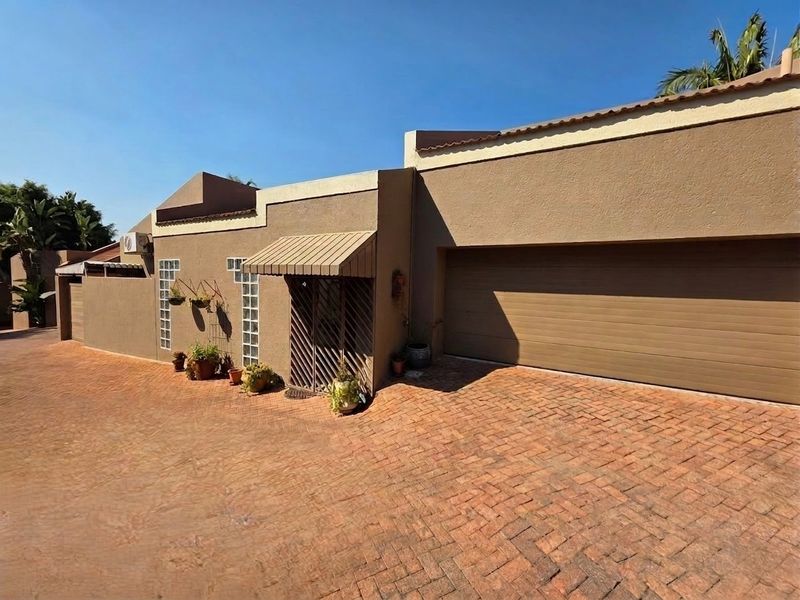 Front exterior view of the property featuring a paved driveway, a double garage, and a secure entrance with an awning.