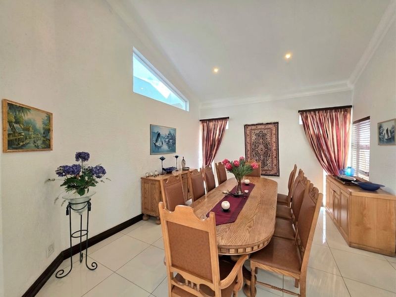 Spacious dining room featuring high vaulted ceilings, large triangular clerestory windows for natural light, and polished tiled flooring.