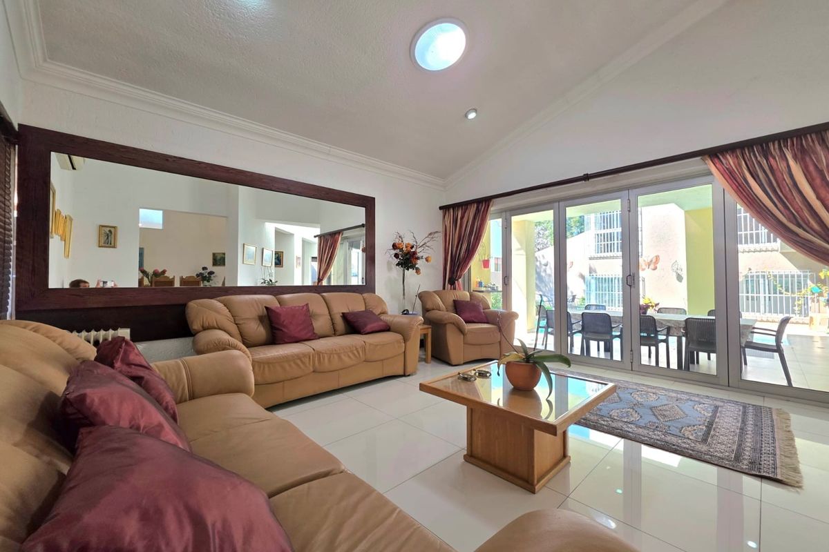 Spacious living room featuring large sliding glass doors leading to a patio, tiled flooring, recessed lighting, and a large decorative wall mirror.
