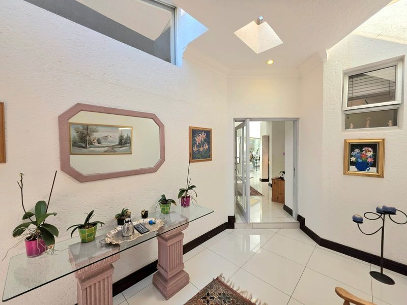 Bright and spacious entrance hall featuring high ceilings, a skylight, and polished tiled flooring, providing a welcoming transition into the home.