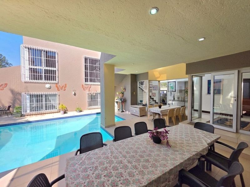 Covered outdoor patio area overlooking a swimming pool, featuring tiled flooring, recessed lighting, and direct access to the interior living spaces.