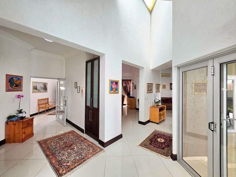 Spacious entrance hall featuring high ceilings with a skylight, tiled flooring, and built-in storage cabinetry, providing a bright and welcoming transition area.
