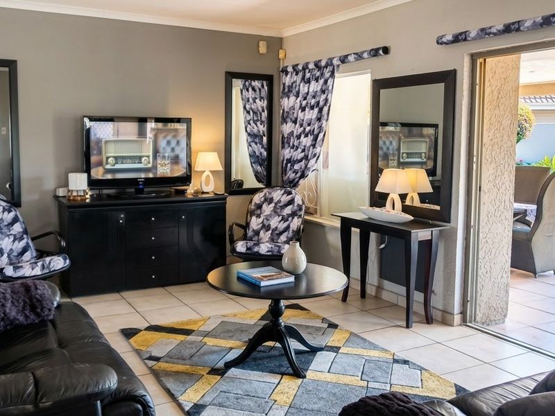 A comfortable living room featuring tiled flooring and a sliding glass door that provides direct access to the outdoor pool area.