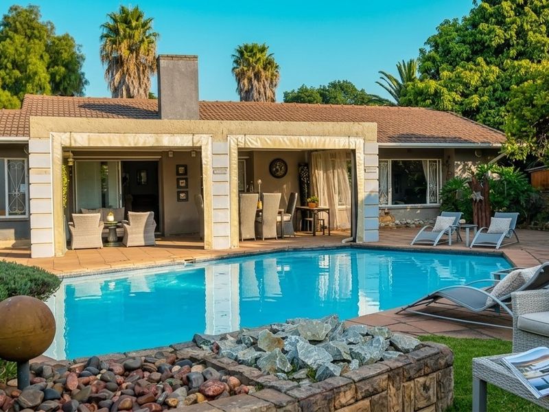 A well-maintained backyard featuring a swimming pool, a covered patio area, and a stone-built fire pit, perfect for outdoor entertaining.
