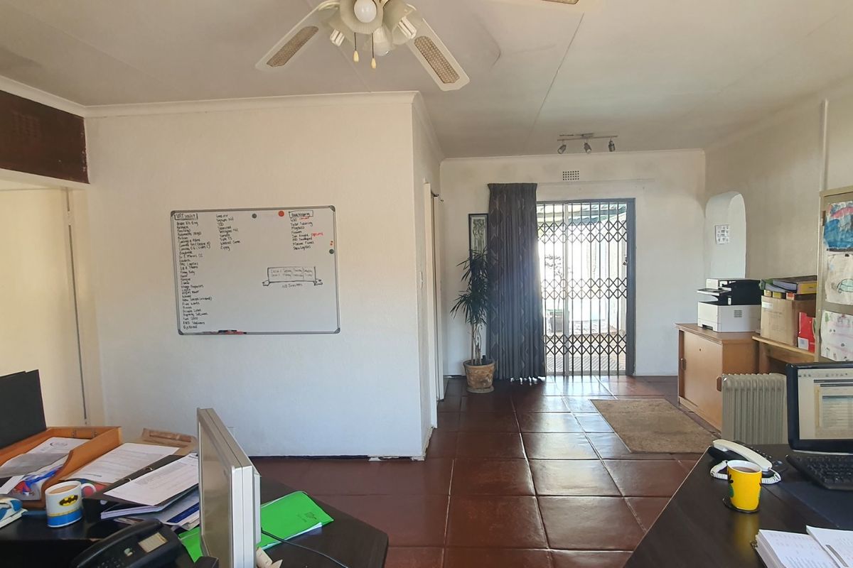 A living area featuring tiled flooring, an exposed brick feature wall, and a security gate leading to the exterior.