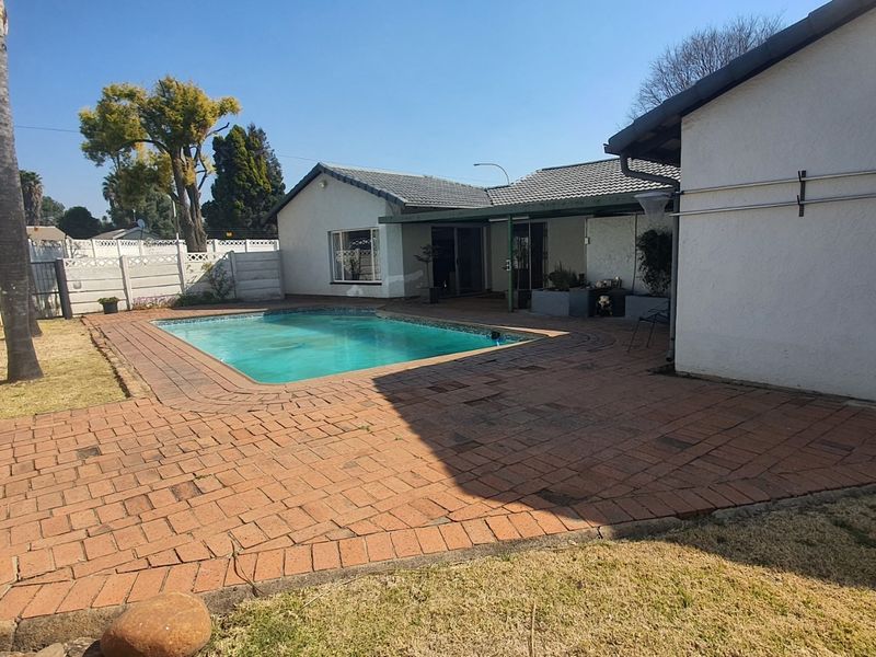 Rear exterior view featuring a swimming pool, brick paved patio area, and perimeter precast walling.