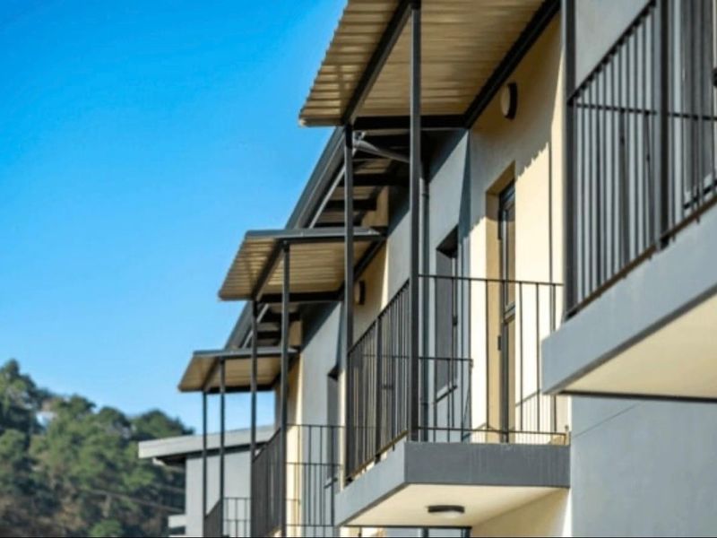 Exterior view of apartment building featuring modern balconies with metal railings and protective roof overhangs.
