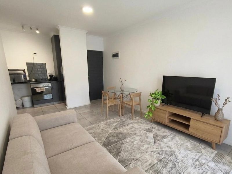 An open-plan living and kitchen area featuring tiled flooring, modern cabinetry, and a built-in oven, creating a functional and cohesive living space.