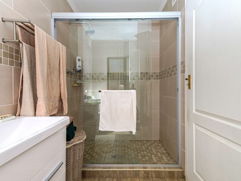 A functional bathroom featuring a walk-in shower with a glass enclosure, tiled walls, and a modern vanity basin.