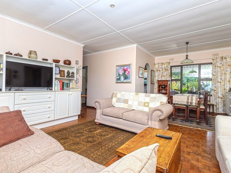 Open plan living and dining area featuring parquet flooring, built-in cabinetry, and direct access to the garden through sliding glass doors.
