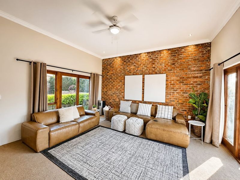 Spacious living room featuring a prominent exposed brick feature wall, ceiling fan, and large sliding glass doors providing ample natural light.