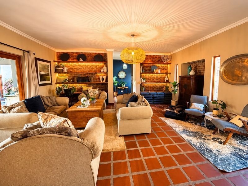 Spacious living room featuring warm terracotta tile flooring, exposed brick feature walls with built-in shelving, and direct access to an outdoor patio area.