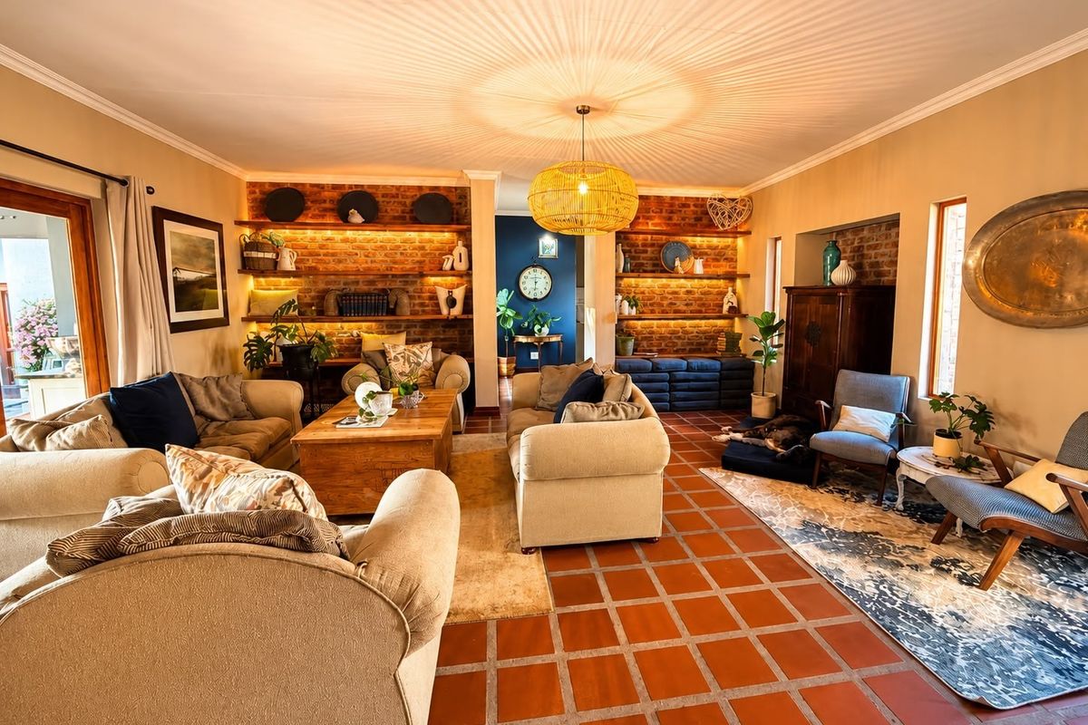 Spacious living room featuring warm terracotta tile flooring, exposed brick feature walls with built-in shelving, and direct access to an outdoor patio area.
