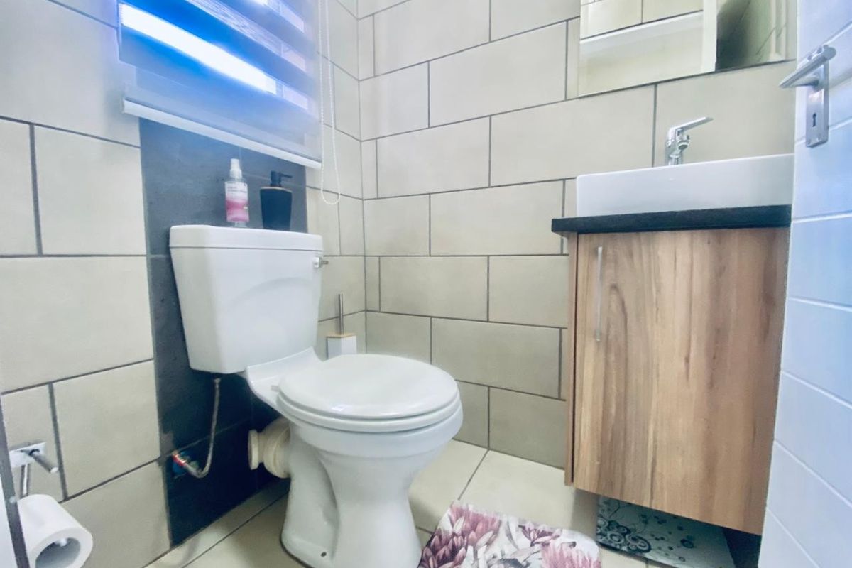 A compact bathroom featuring modern tiled walls, a vanity cabinet with a basin, and a standard toilet.