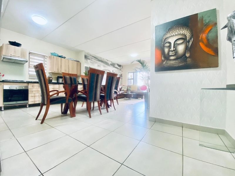 Open-plan living area featuring a modern kitchen with built-in cabinetry, integrated oven, and hob, flowing into a spacious dining and lounge area.