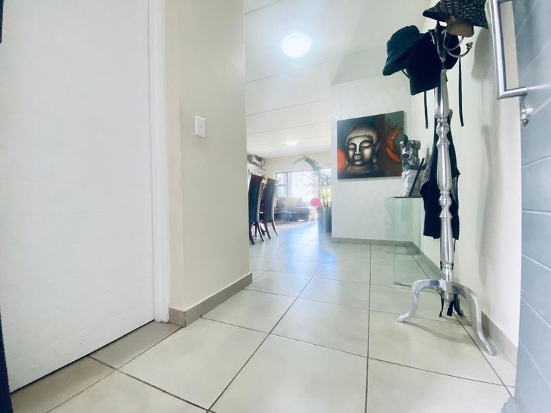 A bright entrance hallway featuring neutral tiled flooring and a direct line of sight into the open-plan living and dining area.