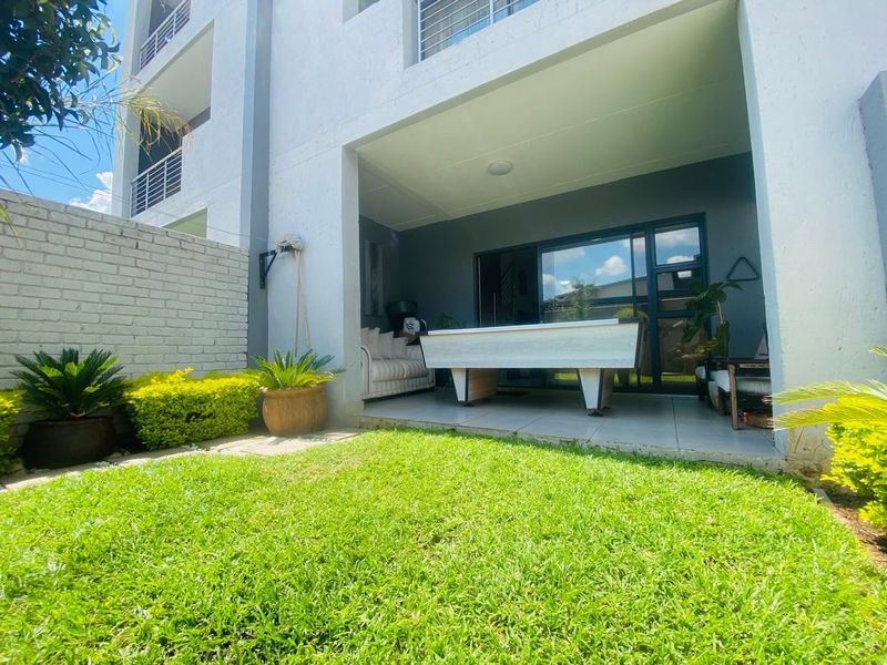 A covered patio area featuring tiled flooring and sliding glass doors, opening onto a private garden space.