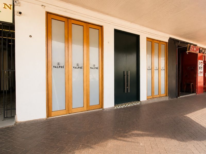 Commercial storefront entrance featuring timber-framed glass doors, a central double door, and a paved covered walkway.