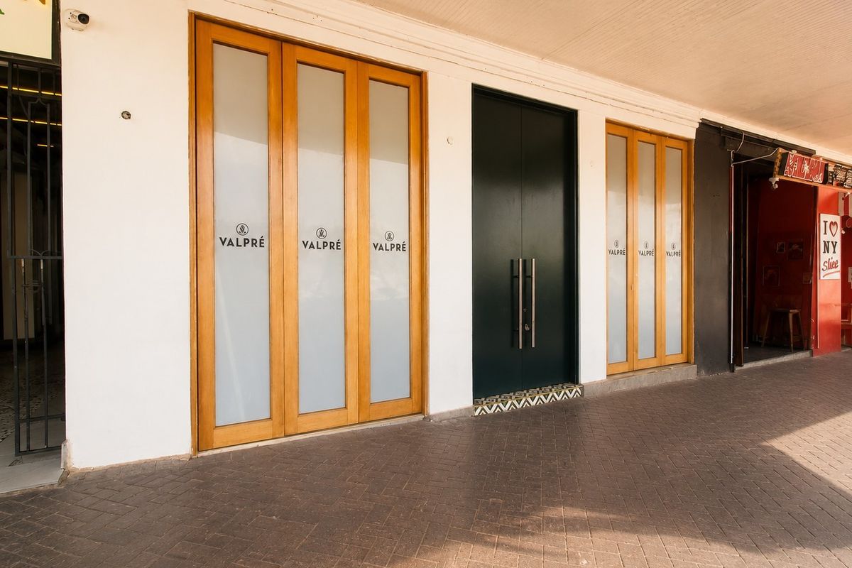 Commercial storefront entrance featuring timber-framed glass doors, a central double door, and a paved covered walkway.