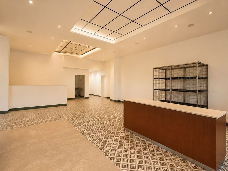 Spacious commercial open-plan area featuring patterned tile flooring, recessed coffered ceiling lighting, and a built-in service counter, suitable for retail or office use.