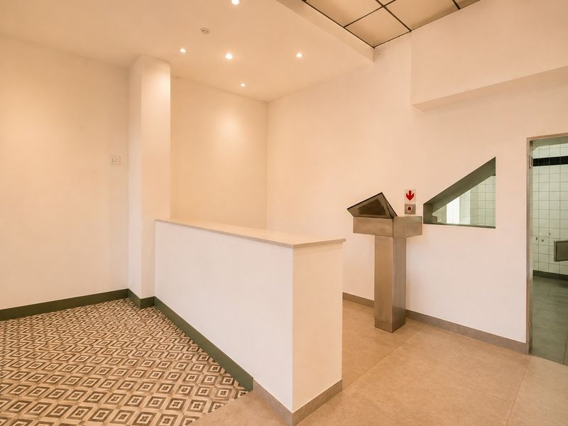 A clean, modern commercial entry area featuring a reception counter, recessed lighting, and a mix of patterned and neutral floor tiling.