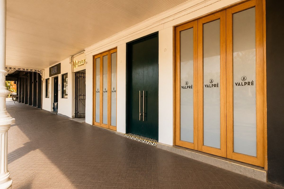 Commercial storefront entrance featuring a covered walkway, tiled flooring, and modern timber-framed glass doors with professional signage.