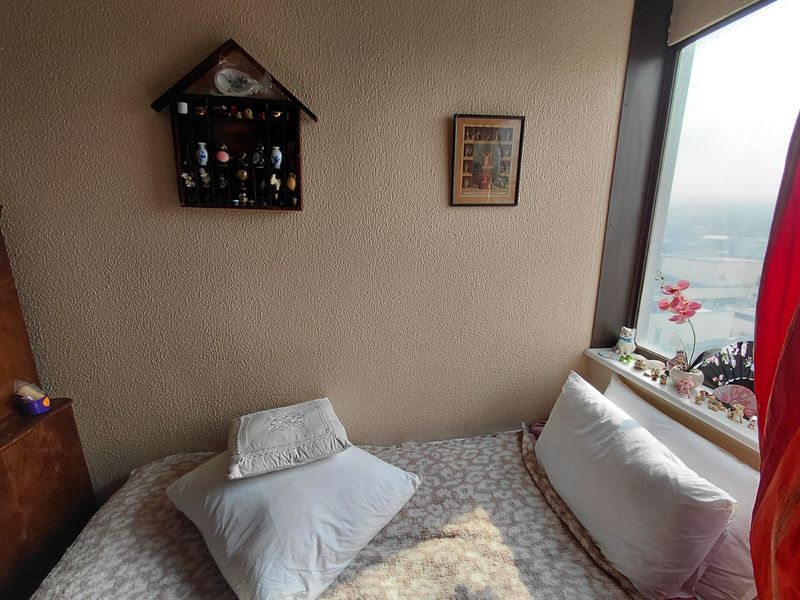 A bedroom featuring a large window with natural light and textured wall finishes, offering a comfortable space within the retirement village.