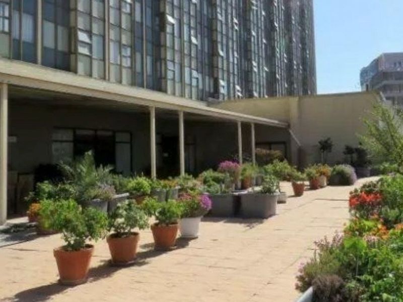 A spacious outdoor terrace area featuring paved flooring and a covered walkway, providing an open-air space for residents.